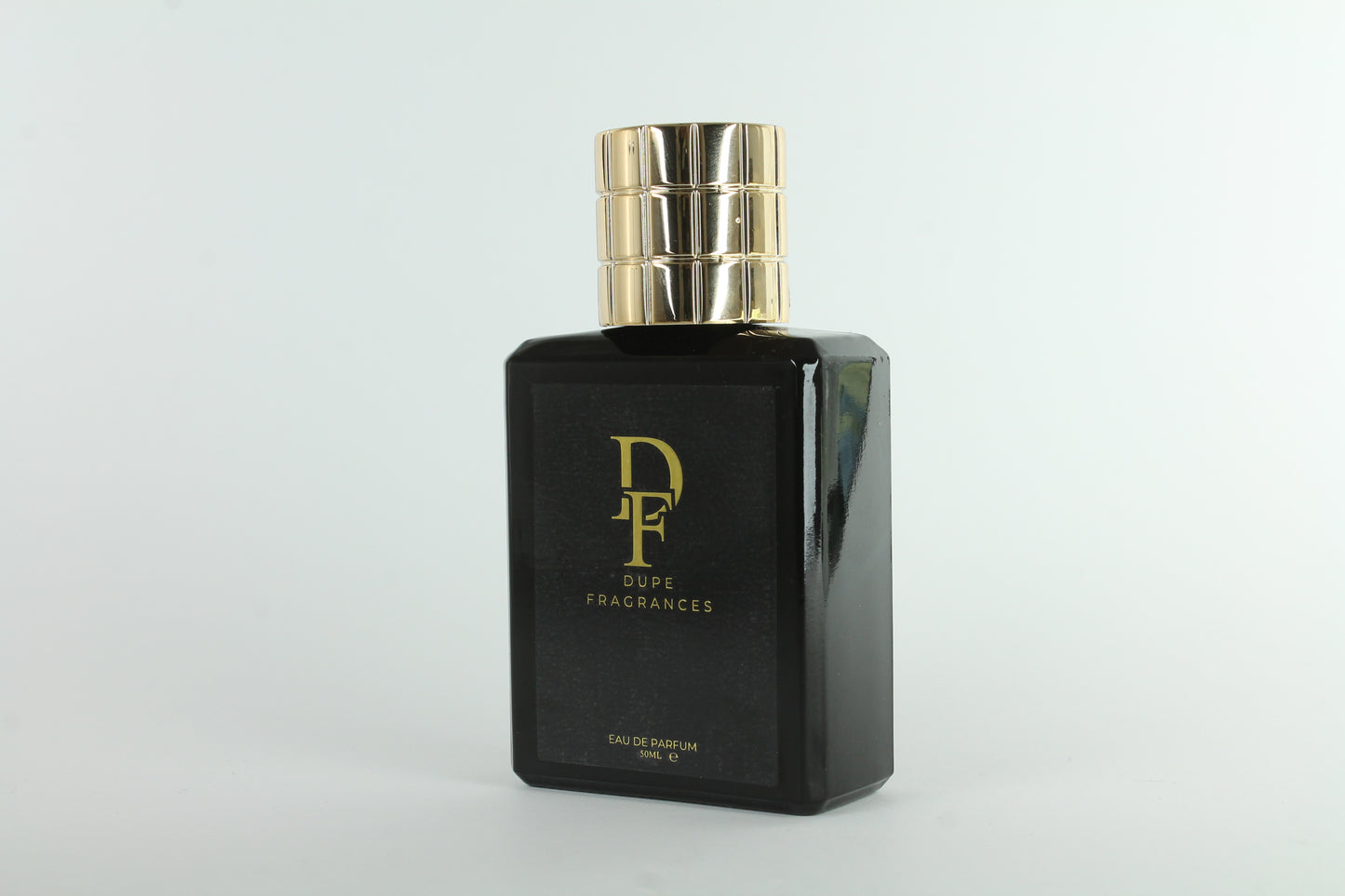 Black perfume bottle with gold cap on a light gray background Dupe fragrances